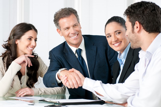 Mature businessman shaking hands to seal a deal with his partner and colleagues in a modern office